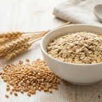 Glutenfreie Haferflocken in einer Schale neben Weizenkoernern - Ueberblick zu glutenfreiem Hafer bei Zoeliakie