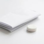 Tablette neben einem Beipackzettel auf weissem Untergrund - Gluten in Medikamenten und Weizenstaerke bei Zoeliakie